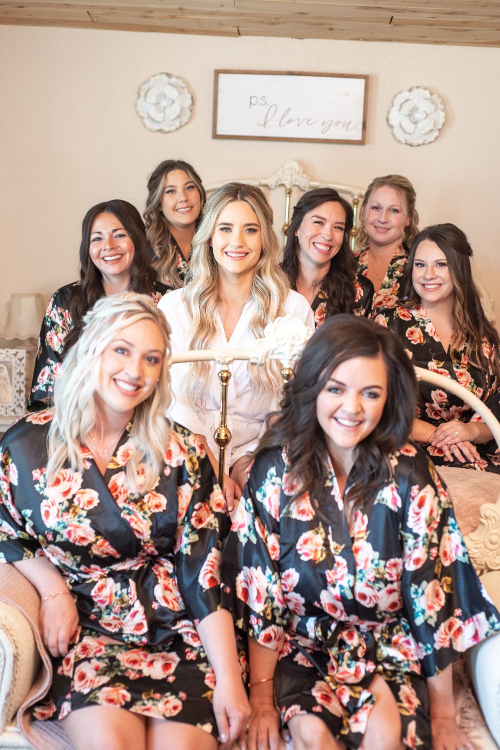 Bridal party sitting together wearing matching floral robes in a decorated room.