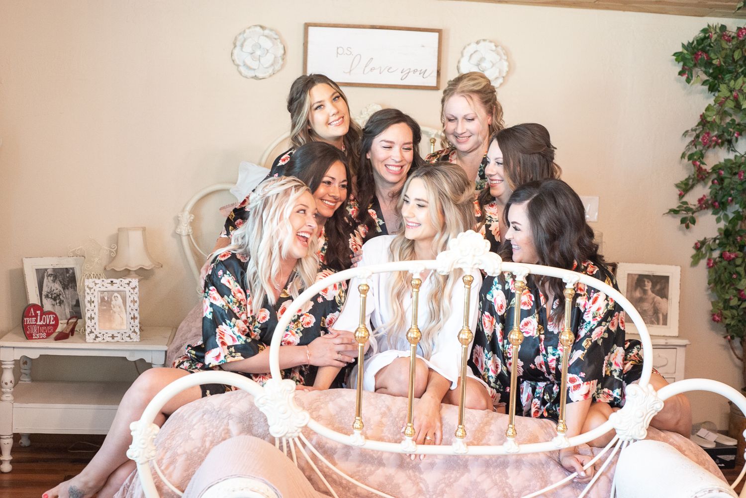Candid moment of bridal party laughing together on a decorative bed.