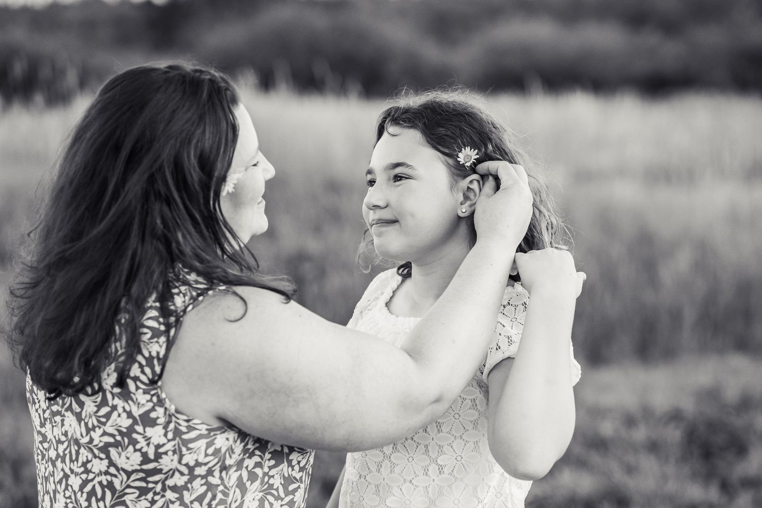 Black and white photo of mother putting daisy in daughters hair in Redmond