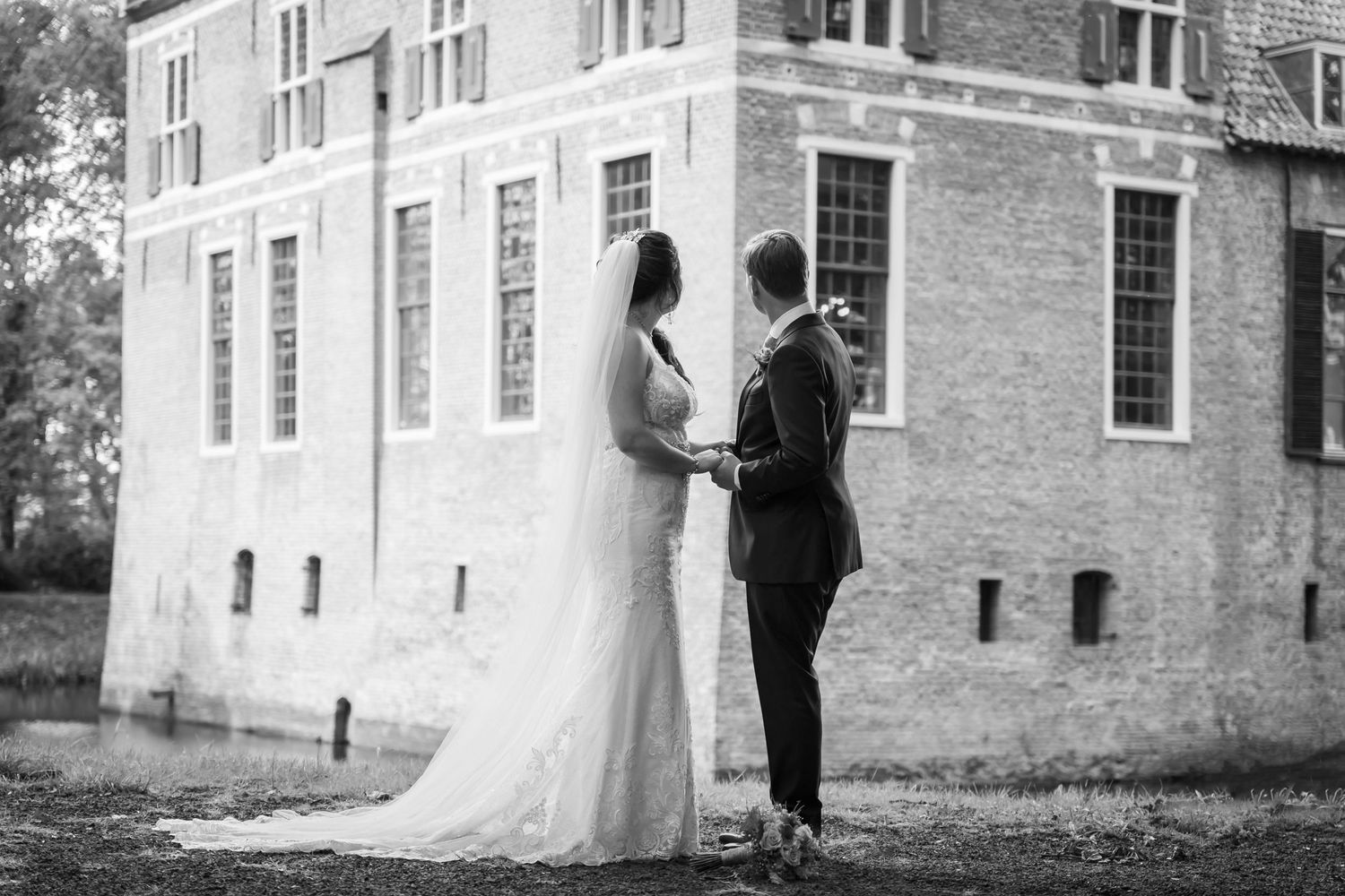 fotoshoot tijdens bruiloft kasteel Wijenburg zwart wit bruidspaar staat voor kasteel trouwlocatie trouwfotografie maas en waal Gelderland