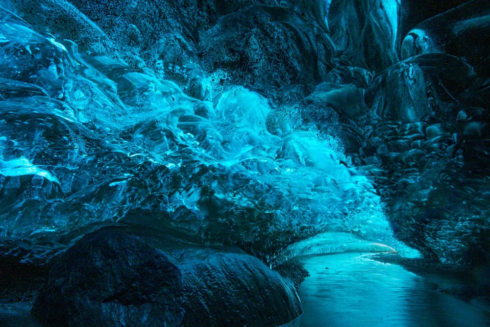 Stunning blue ice cave with glowing crystalline walls and natural arch formations.