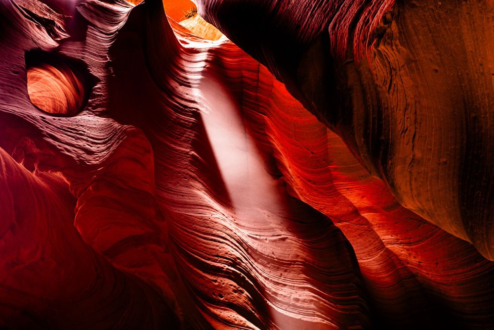 Sunbeam streams through red sandstone walls in Antelope Canyon creating dramatic lighting effects.