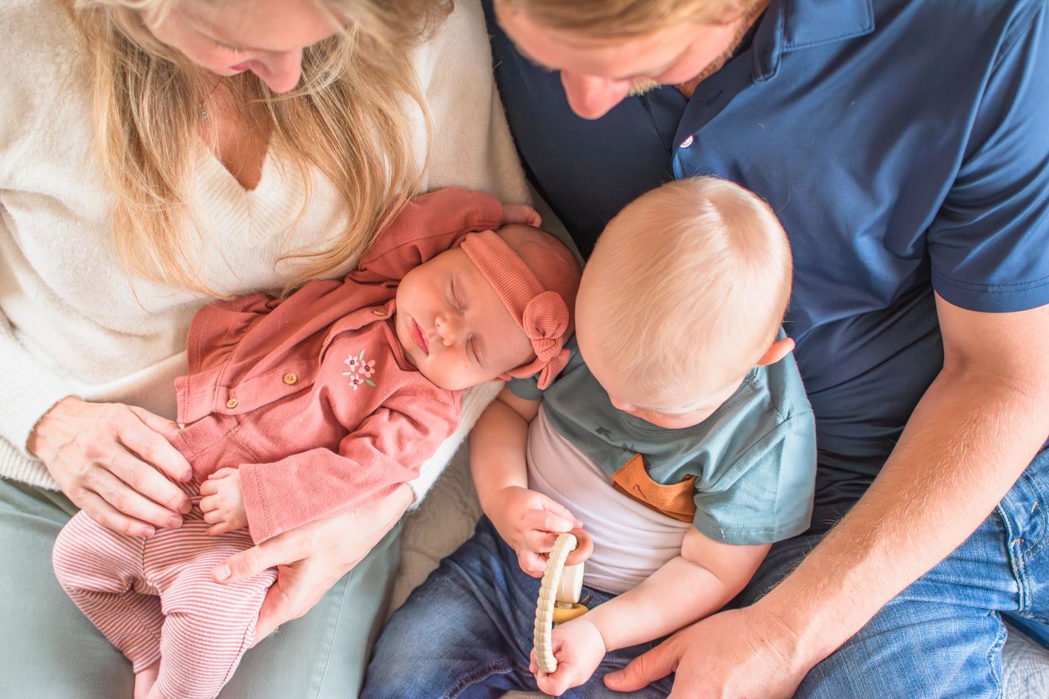 Close-up shot of a family bonding moment with infant in pink and toddler in blue.