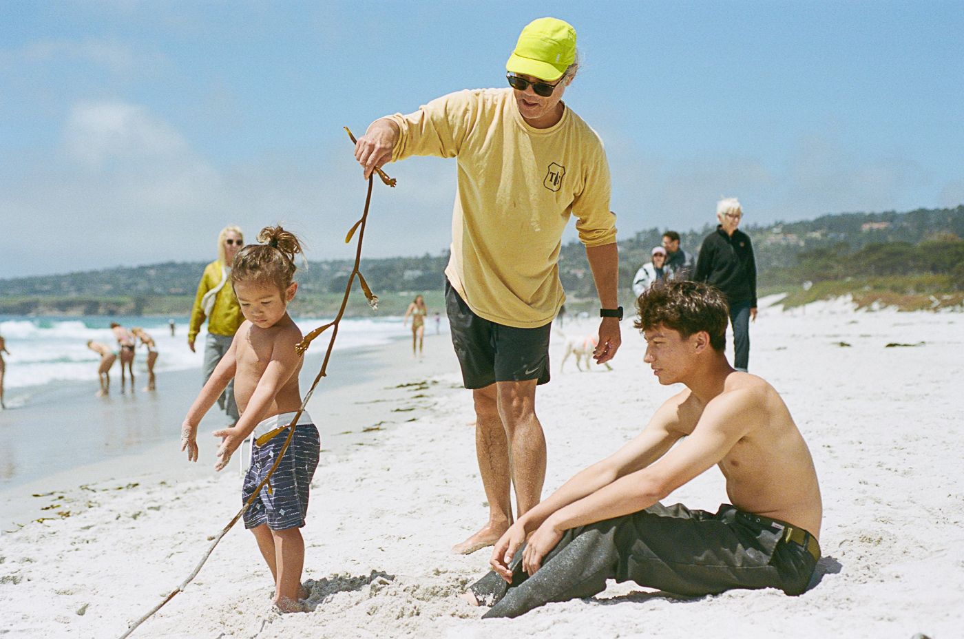 Family enjoying a playful day at the beach with turquoise waters in the background.