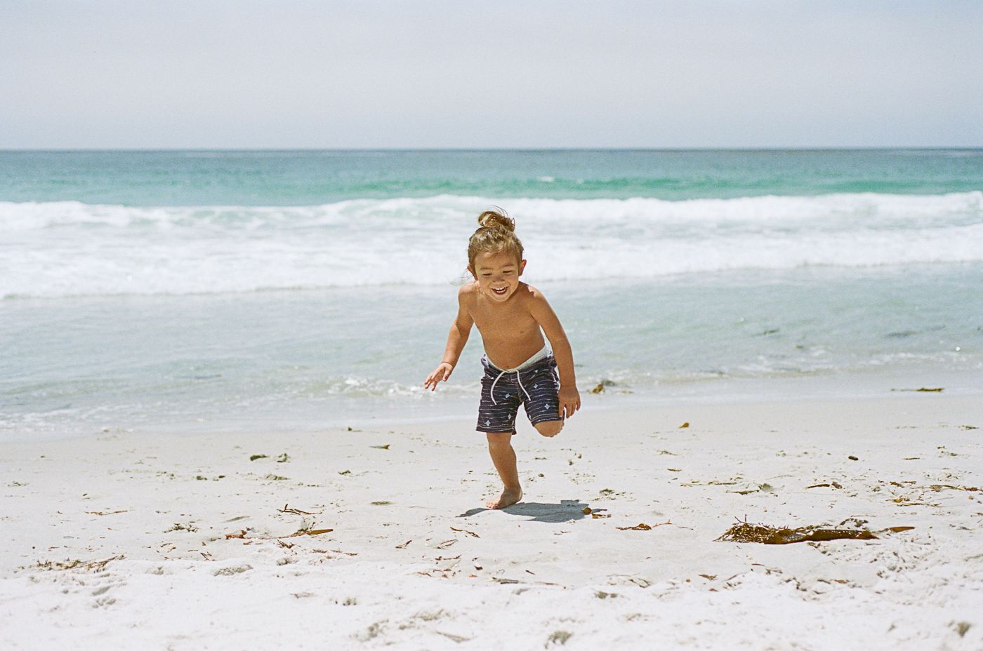 People walking and playing on a pristine white sand beach with turquoise waters.
