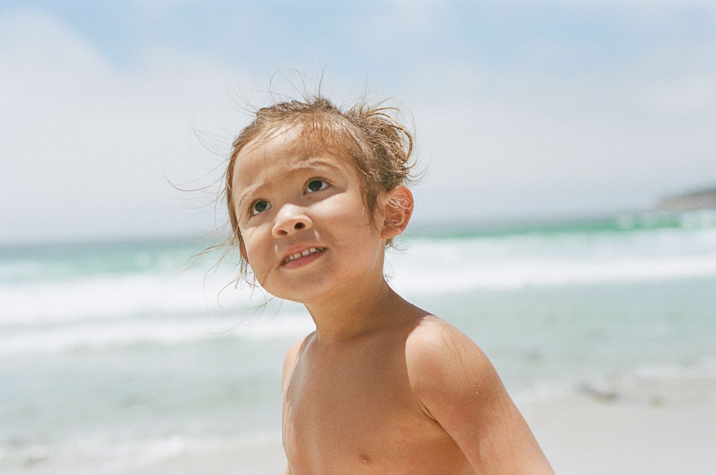 Close up portrait at the beach with ocean waves in the background.