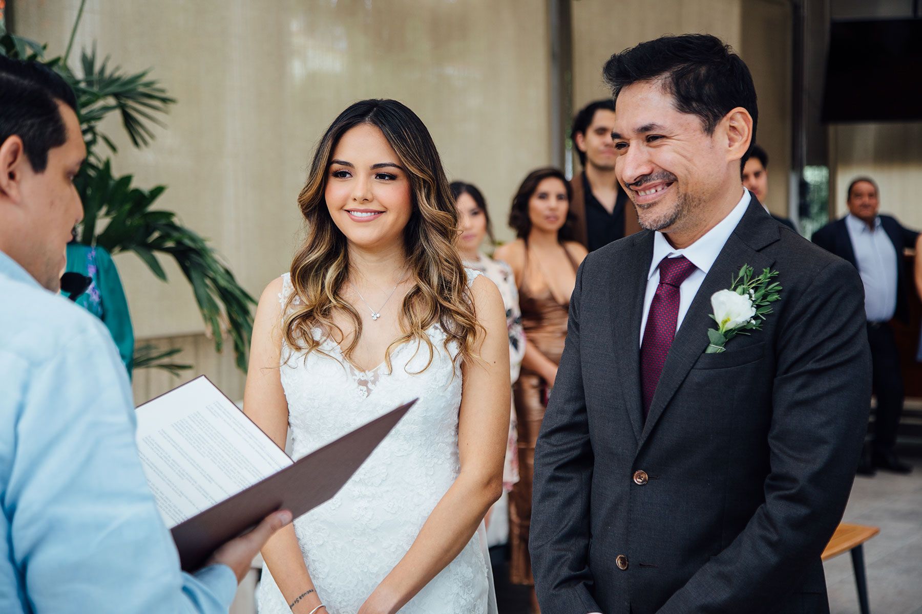 Bride and groom smiling joyfully during wedding ceremony officiated indoors.