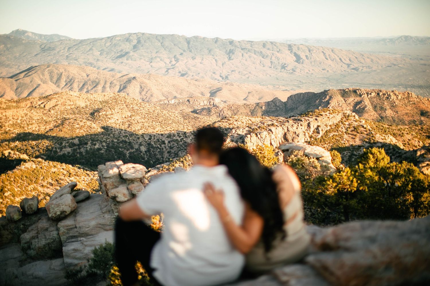 Panoramic desert mountain landscape with couple in foreground during golden hour.