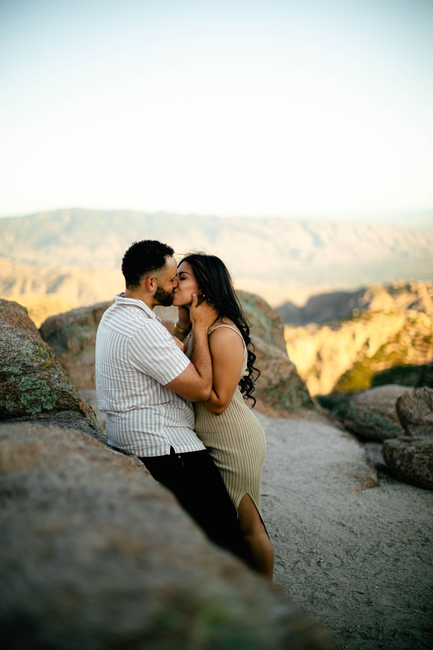 Romantic sunset photoshoot of a couple embracing on rocky desert terrain.