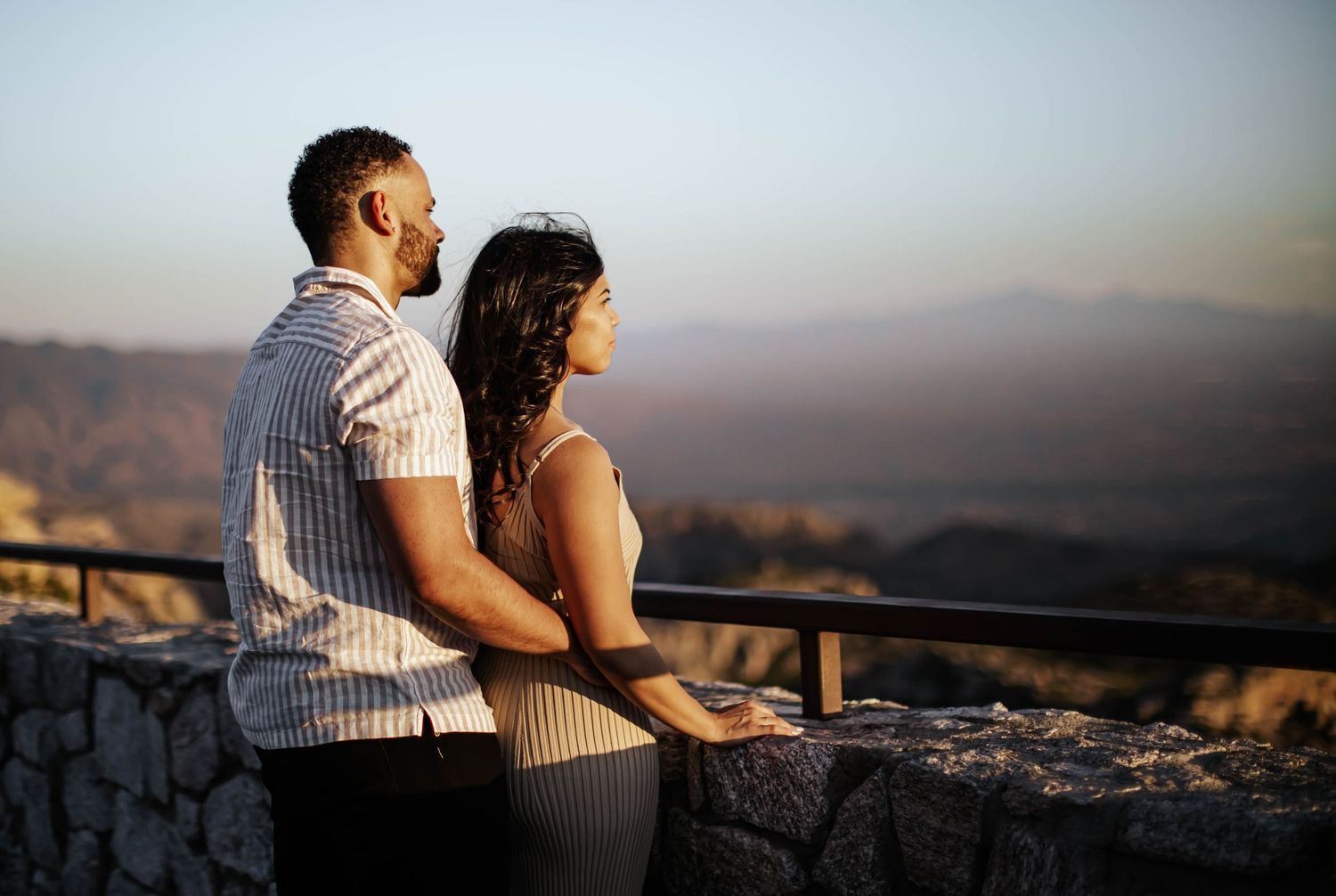 Couple sharing intimate moments against a scenic mountain backdrop at sunset.