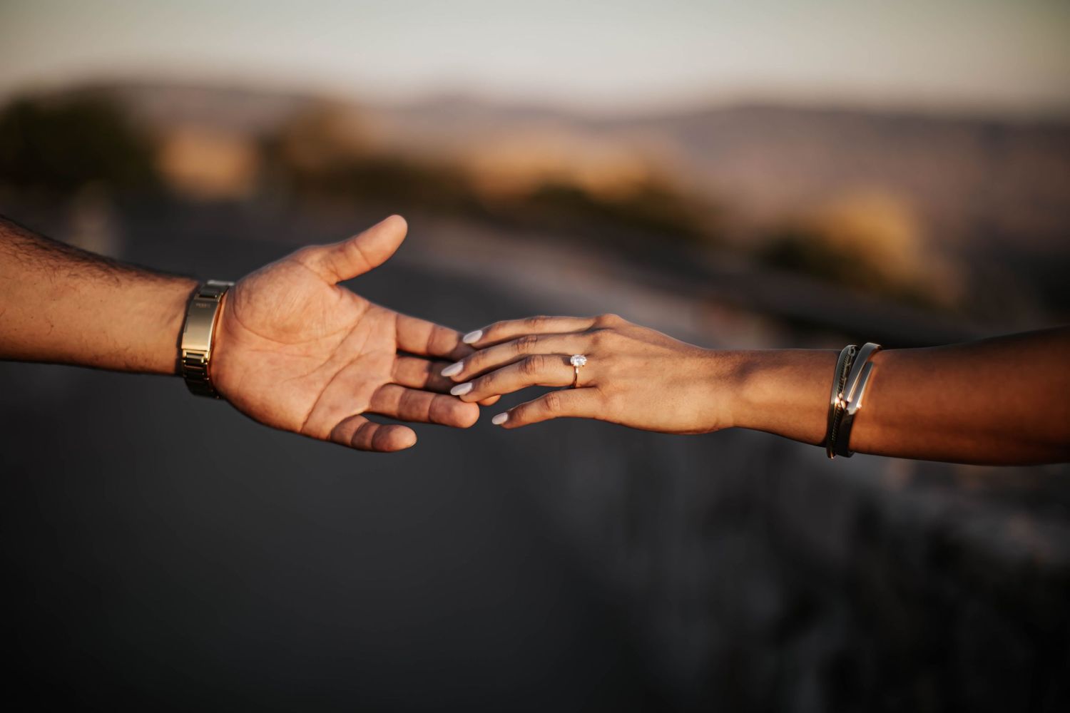 Close-up shot of hands with wedding rings reaching toward each other.