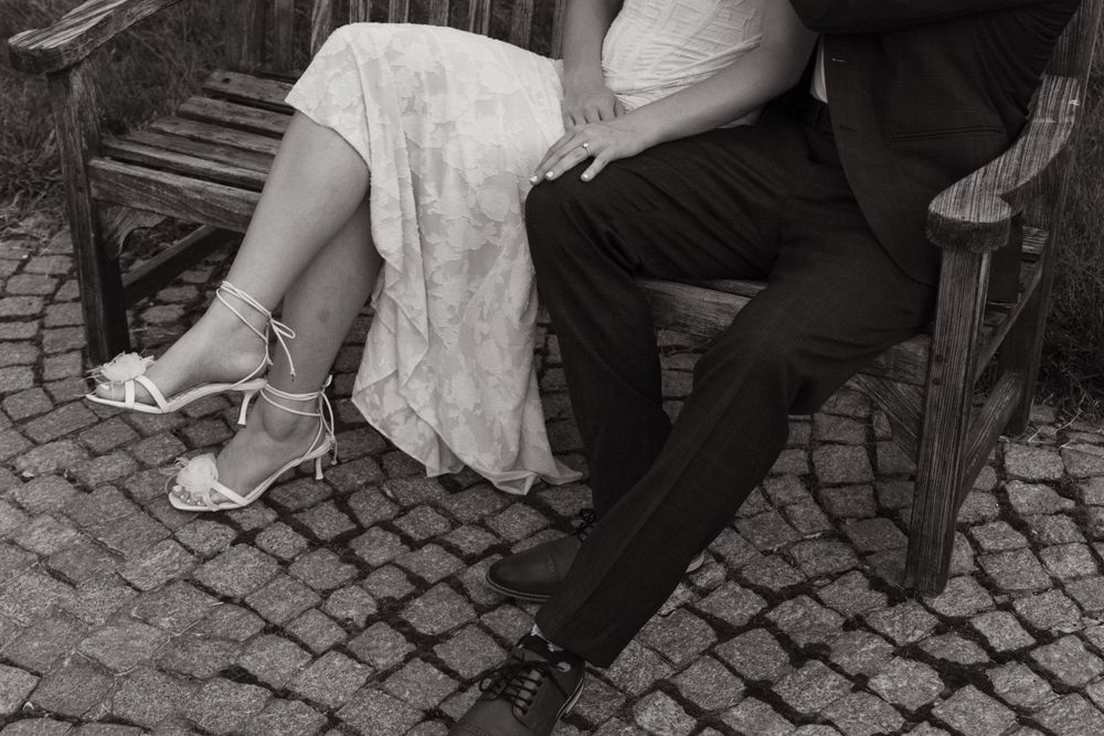 A black and white detail shot of formal attire and shoes on a cobblestone path.