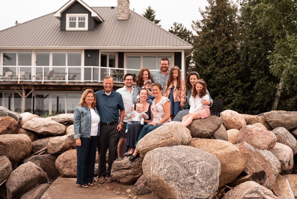 Family group photo on large rocky landscape with grey house in background.