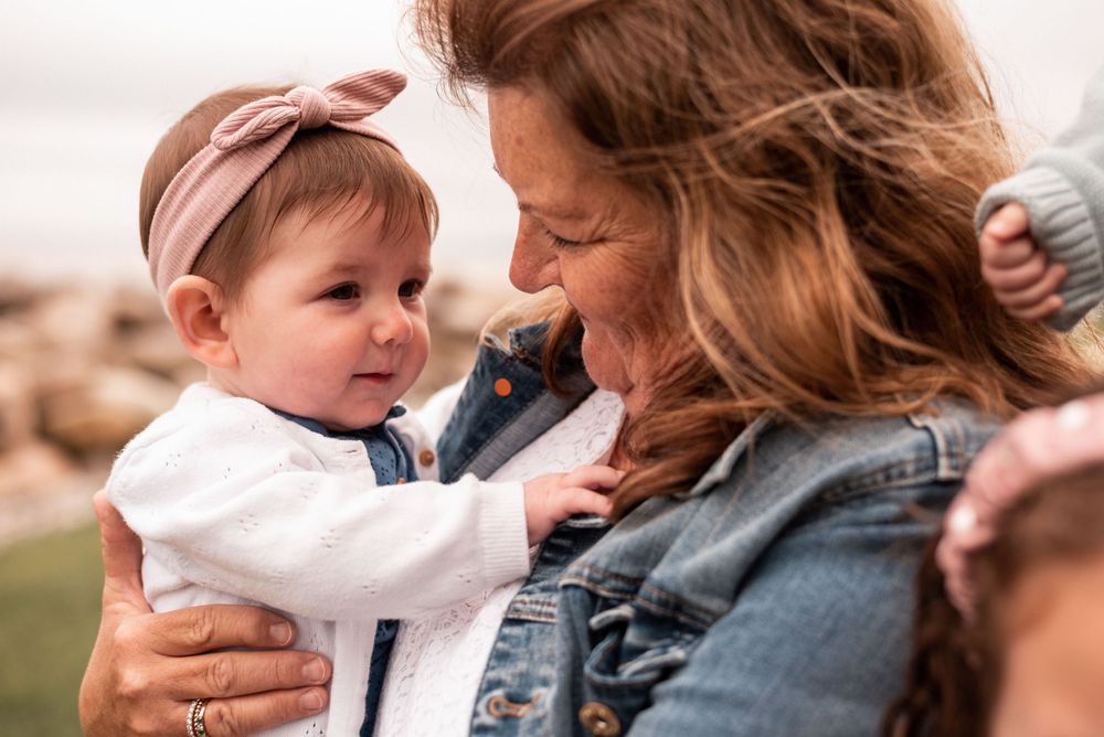 Sweet moment captured between parent and baby wearing pink headband outdoors.