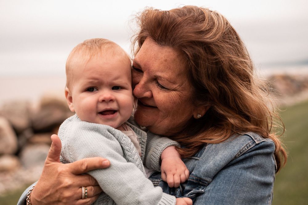 Loving moment between parent in denim jacket and smiling baby.
