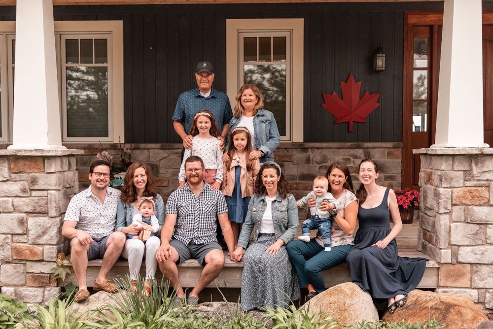 Group portrait of family members sitting on stone porch steps with white columns.