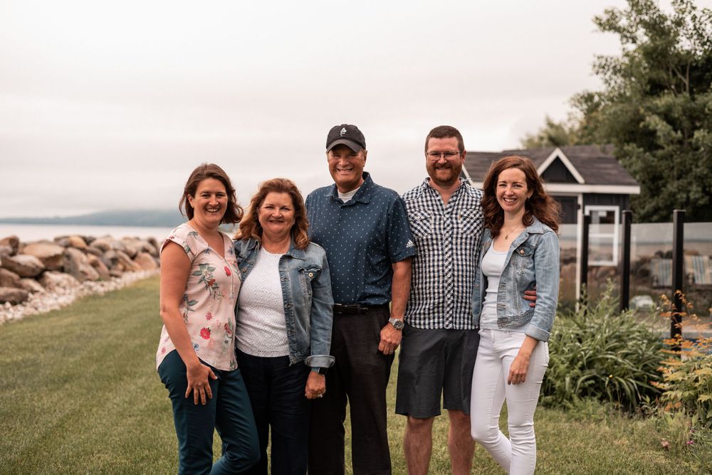 Group photo of five people standing together outdoors near rocky coastline.