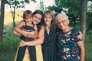 Multi-generational family group posing together outdoors in summer garden setting.