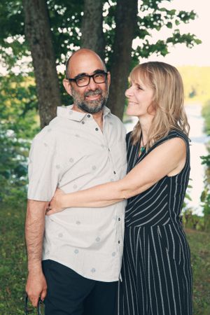 Couple embracing outdoors with trees and evening light in background.
