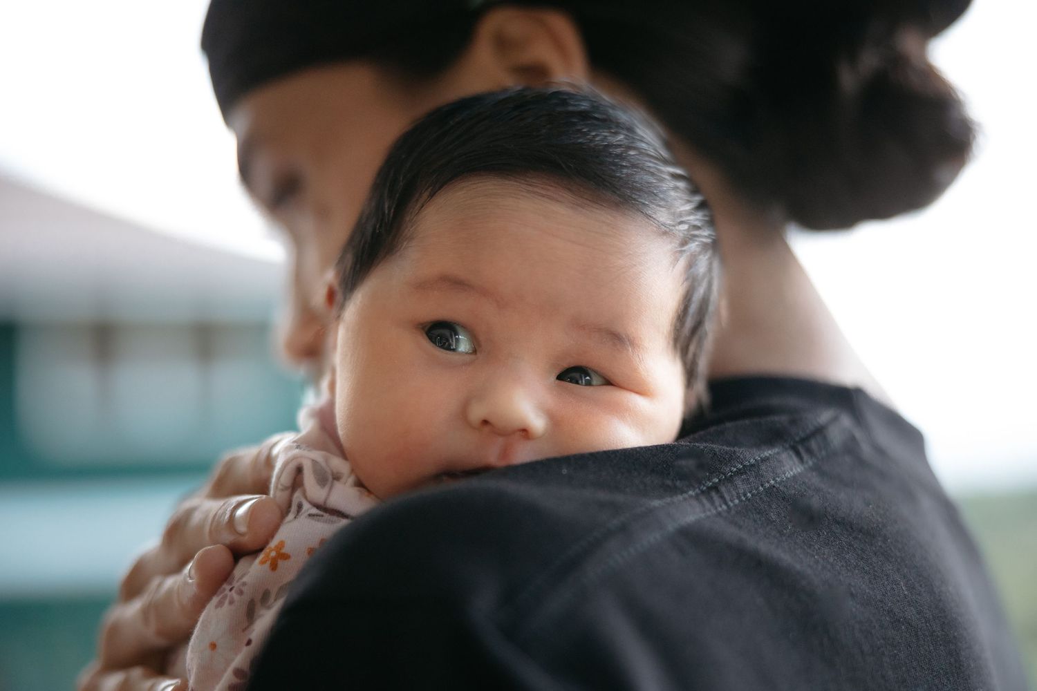 Maui Newborn Photography - A beautiful baby girl looks curiously over her fathers shoulder.