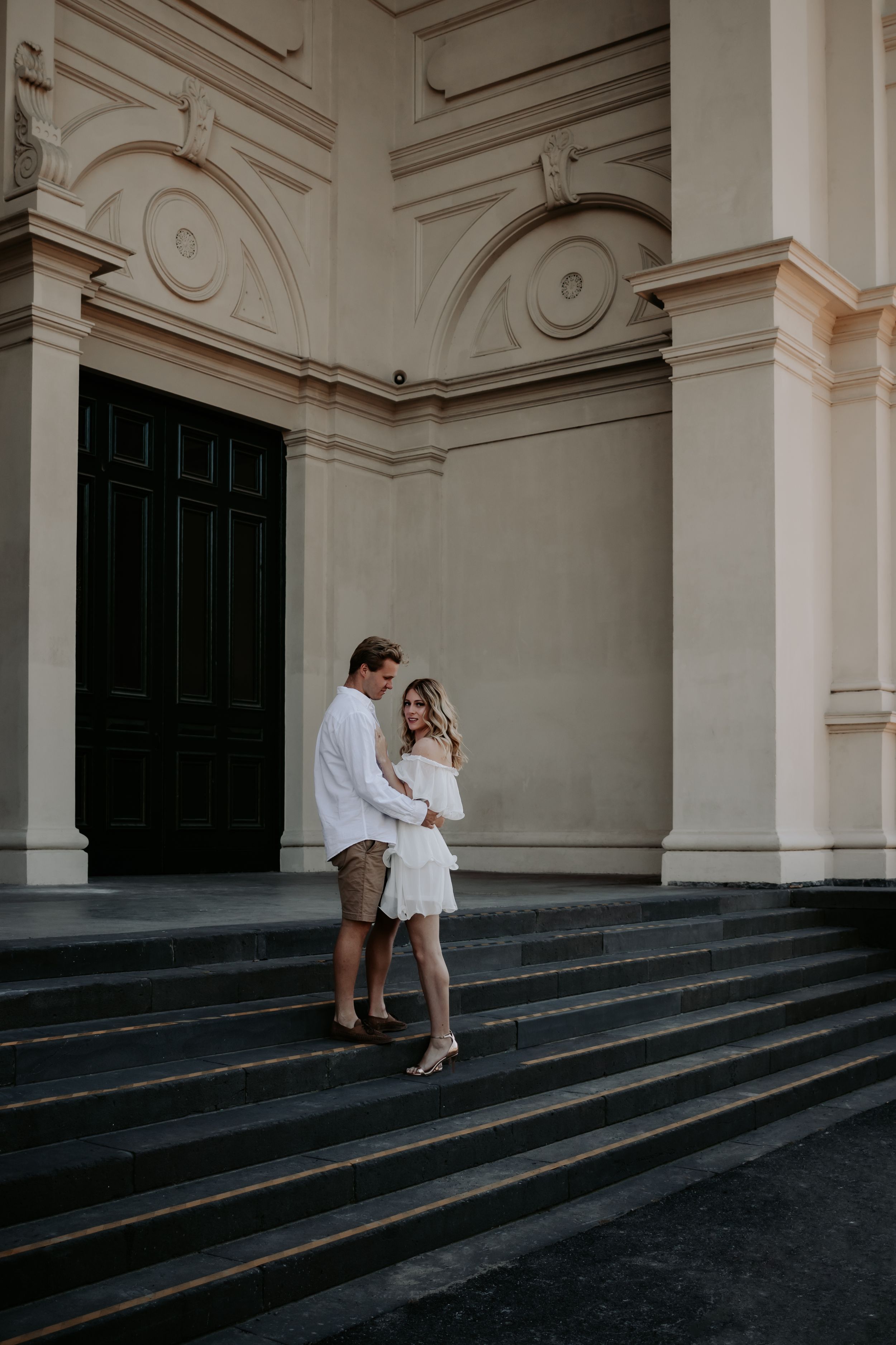 An engaged couple holding each other on stairs.
