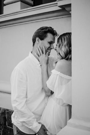 Couple leaning against pillar looking at each other.
