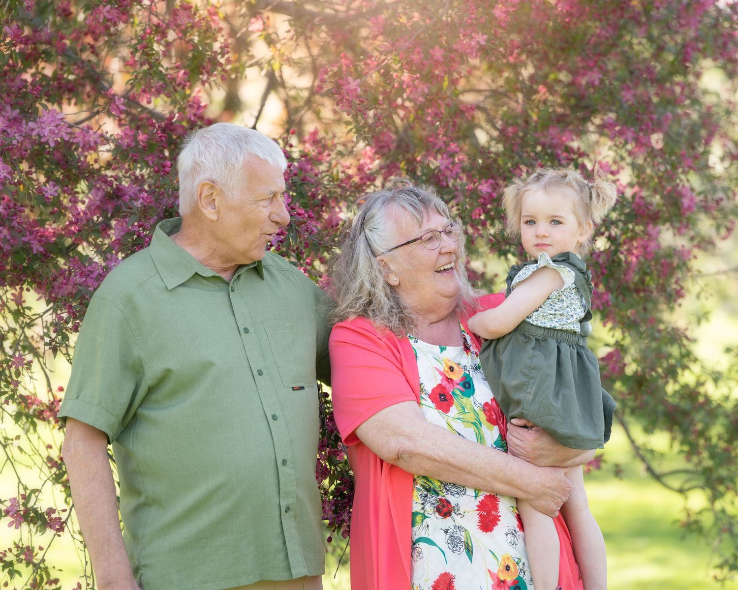 Family moment captured under flowering spring trees with golden sunlight.