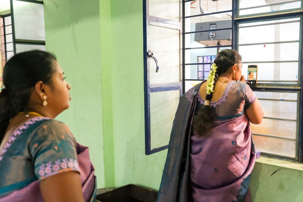 Women in traditional Indian saris looking out through window.