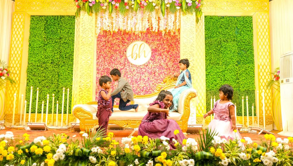 Festive indoor celebration with floral decorations and artificial grass wall panels.