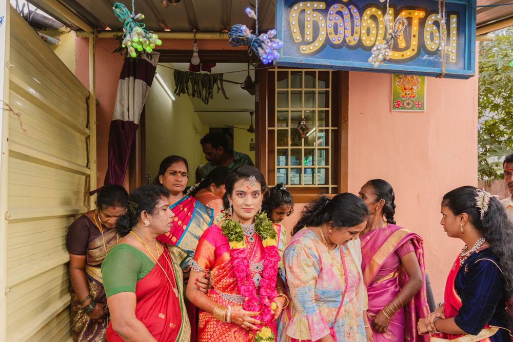 Group gathers outside a doorway with Tamil text sign during celebration.