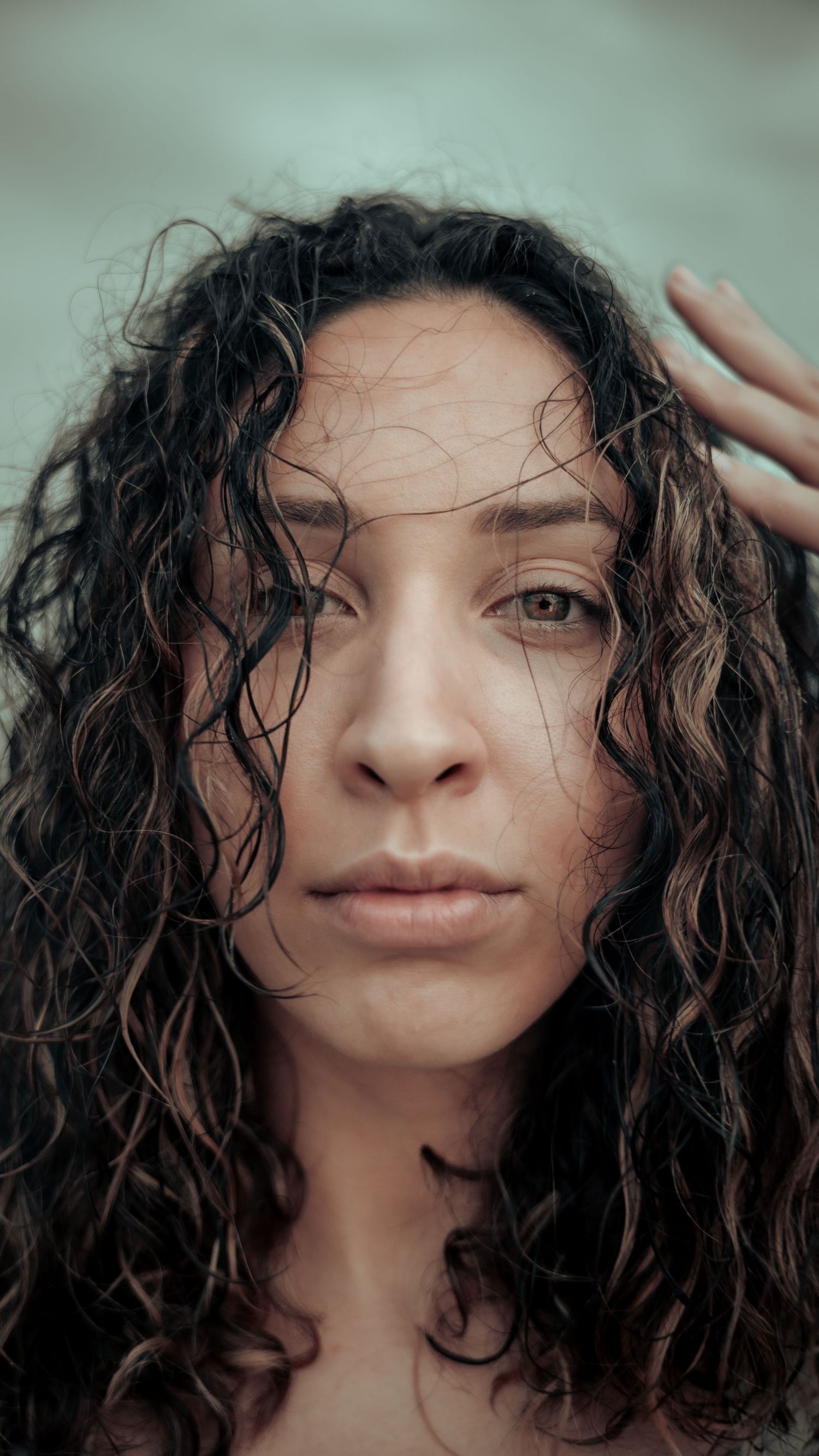 A close-up portrait showing wet curly hair and natural beauty against a soft background.