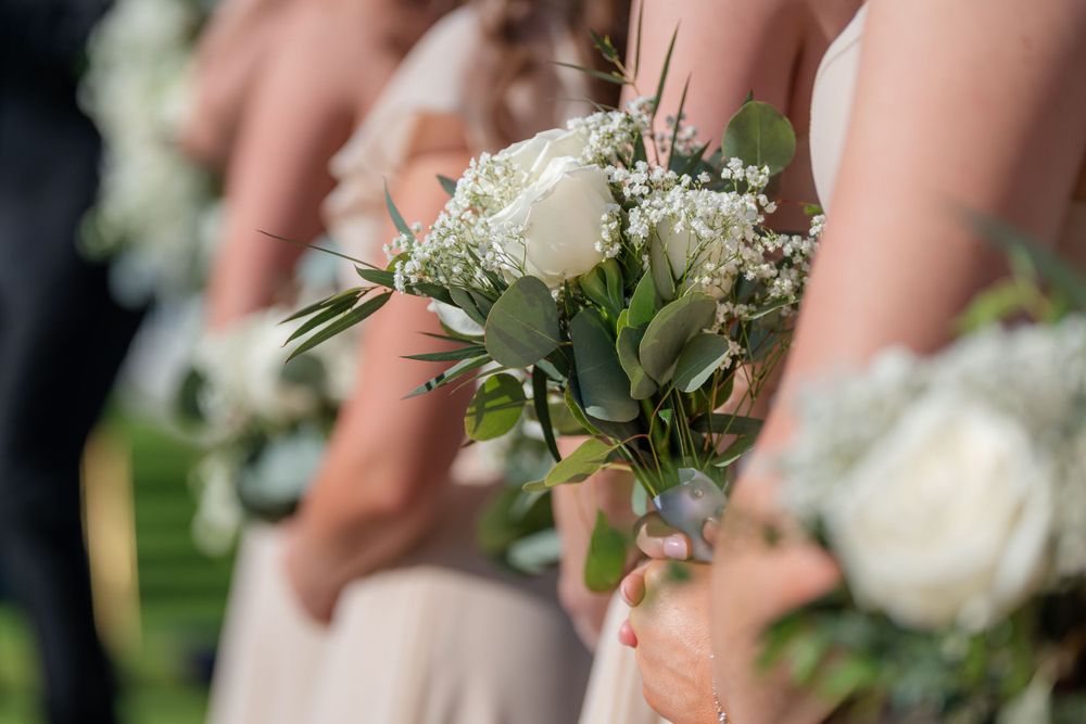 White rose and baby's breath wedding bouquet held against formal attire.