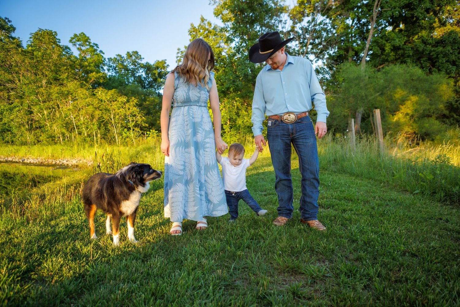 Four siblings walking through a field, holding hands and smiling at each other.