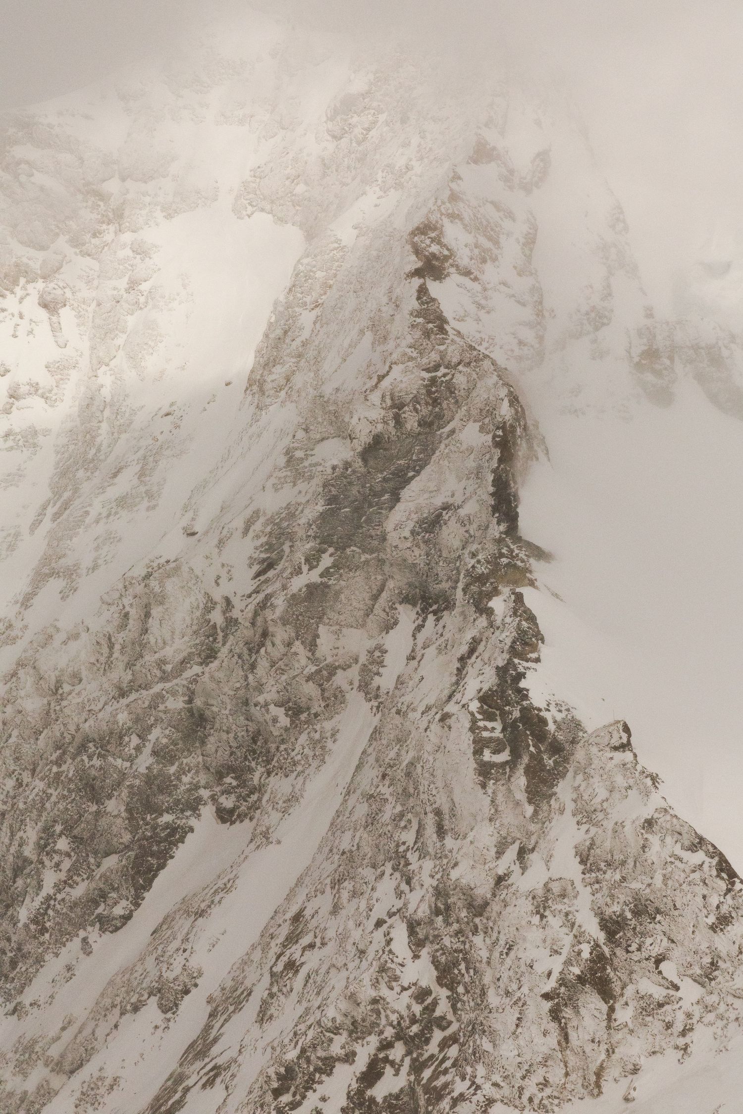 A misty mountain peak covered in snow and rock formations.