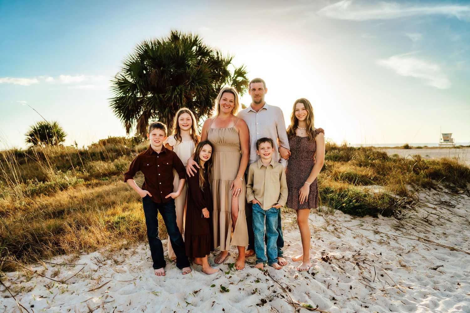 Family playing together on a sandy beach at sunset.