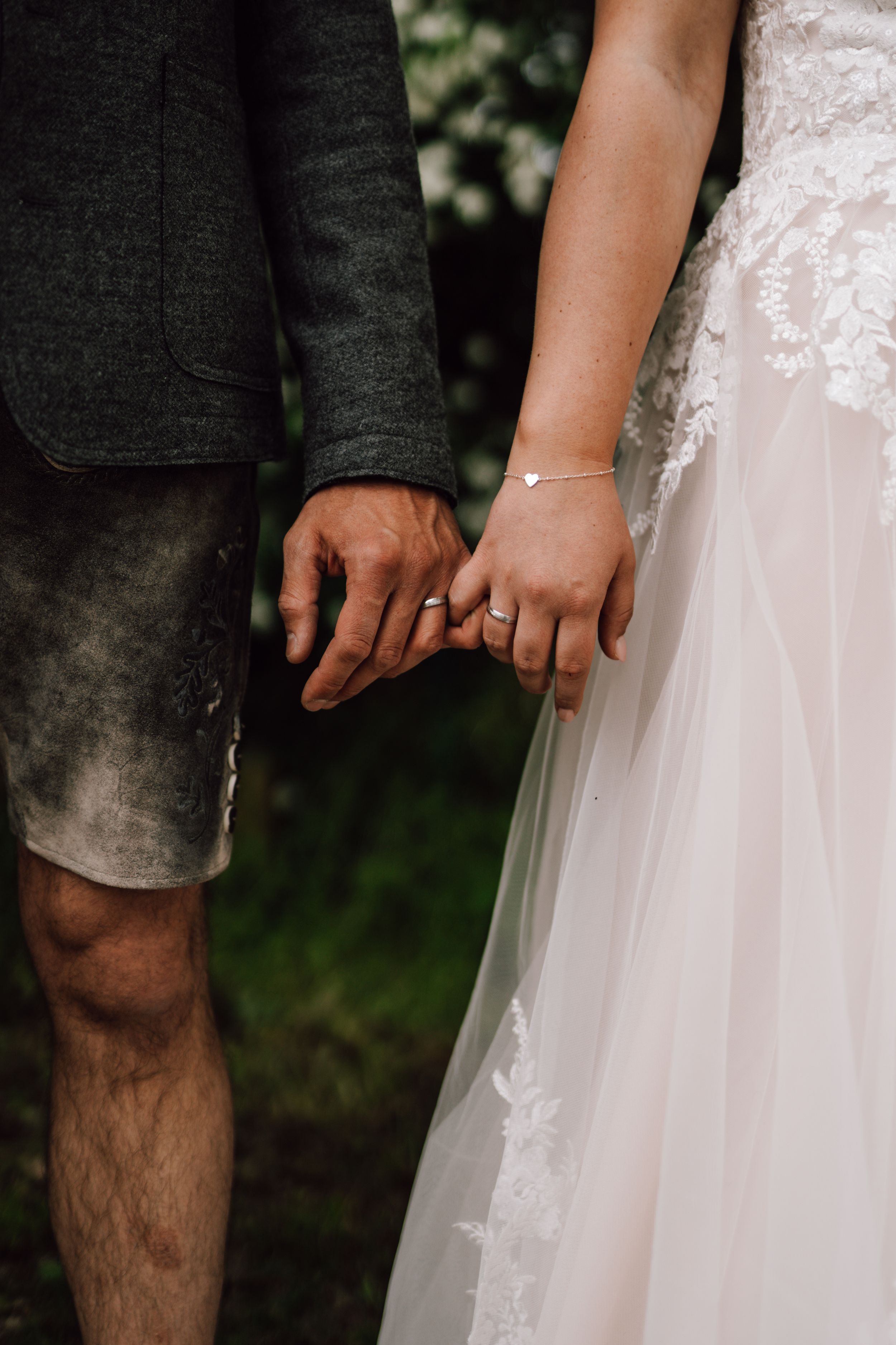 Detail shot of wedding attire showing a white lace dress and dark suit.