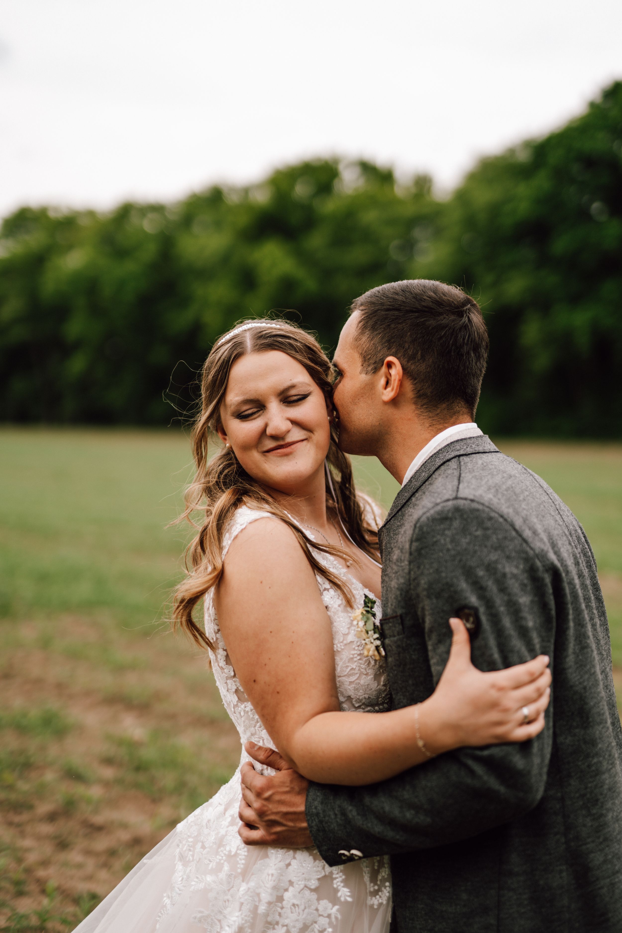 Tender embrace between newlyweds in a rustic outdoor setting.