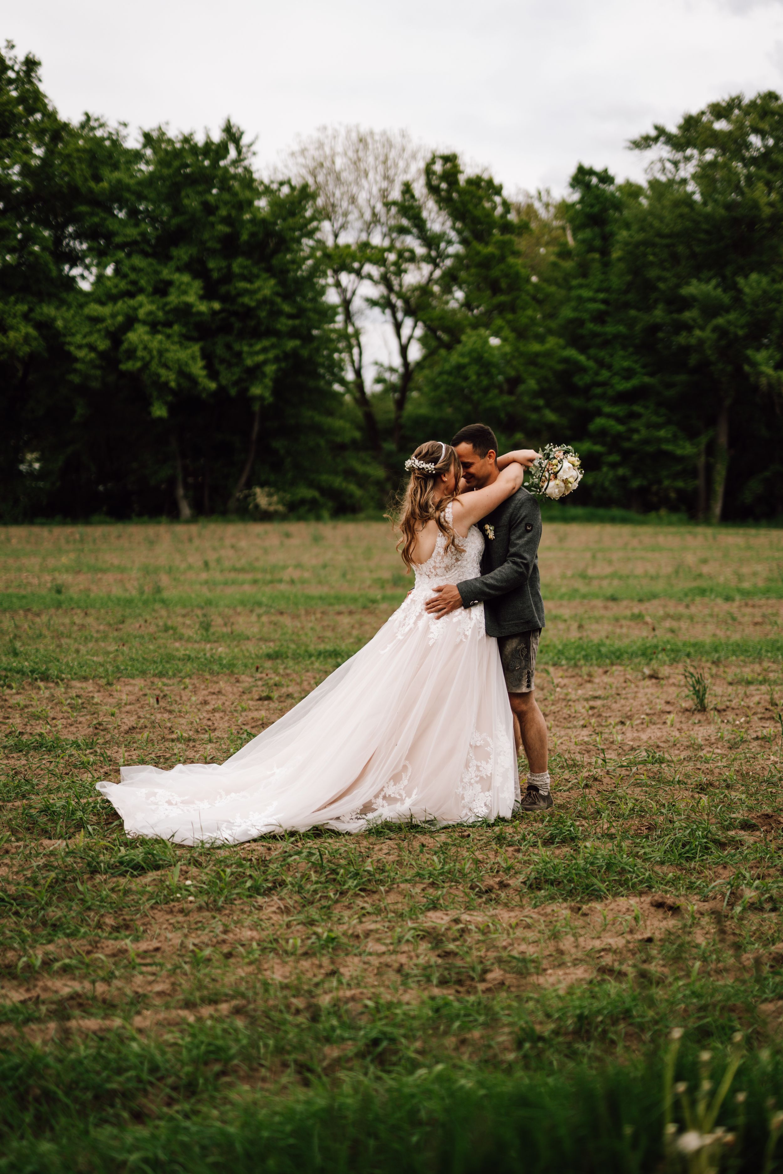 Wedding couple dancing in an open field with the bride's dress flowing beautifully.