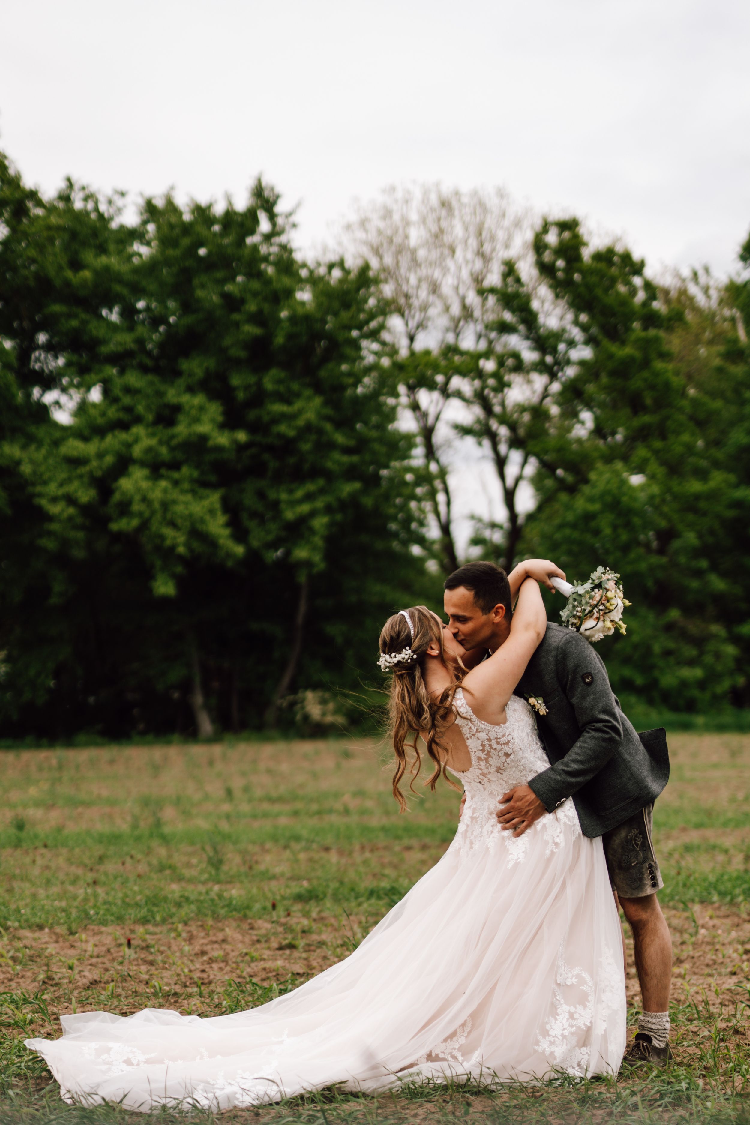 Romantic dip pose in a field showcasing the bride's flowing white gown.