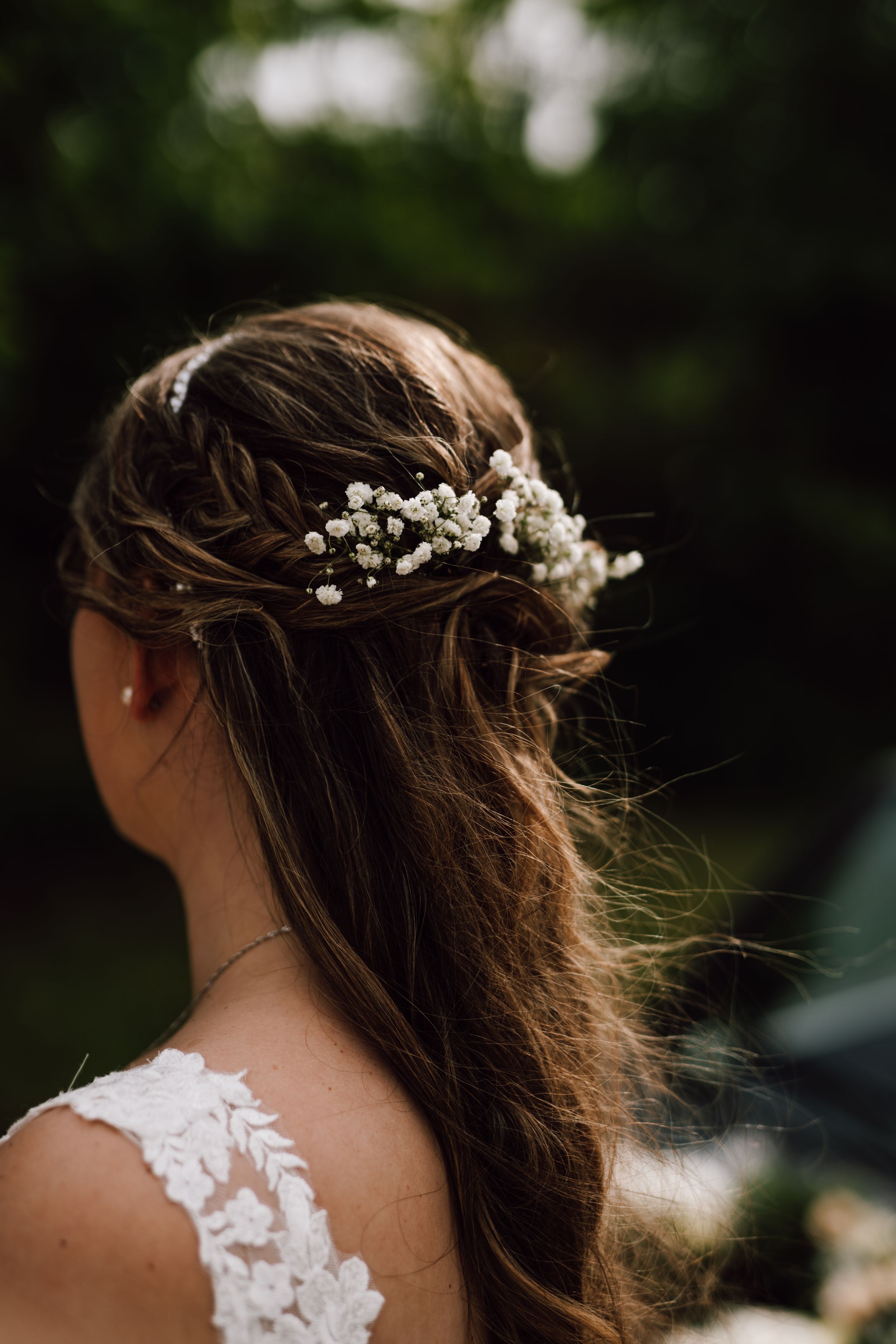 Delicate baby's breath flowers adorn a bride's flowing hair in an artistic detail shot.