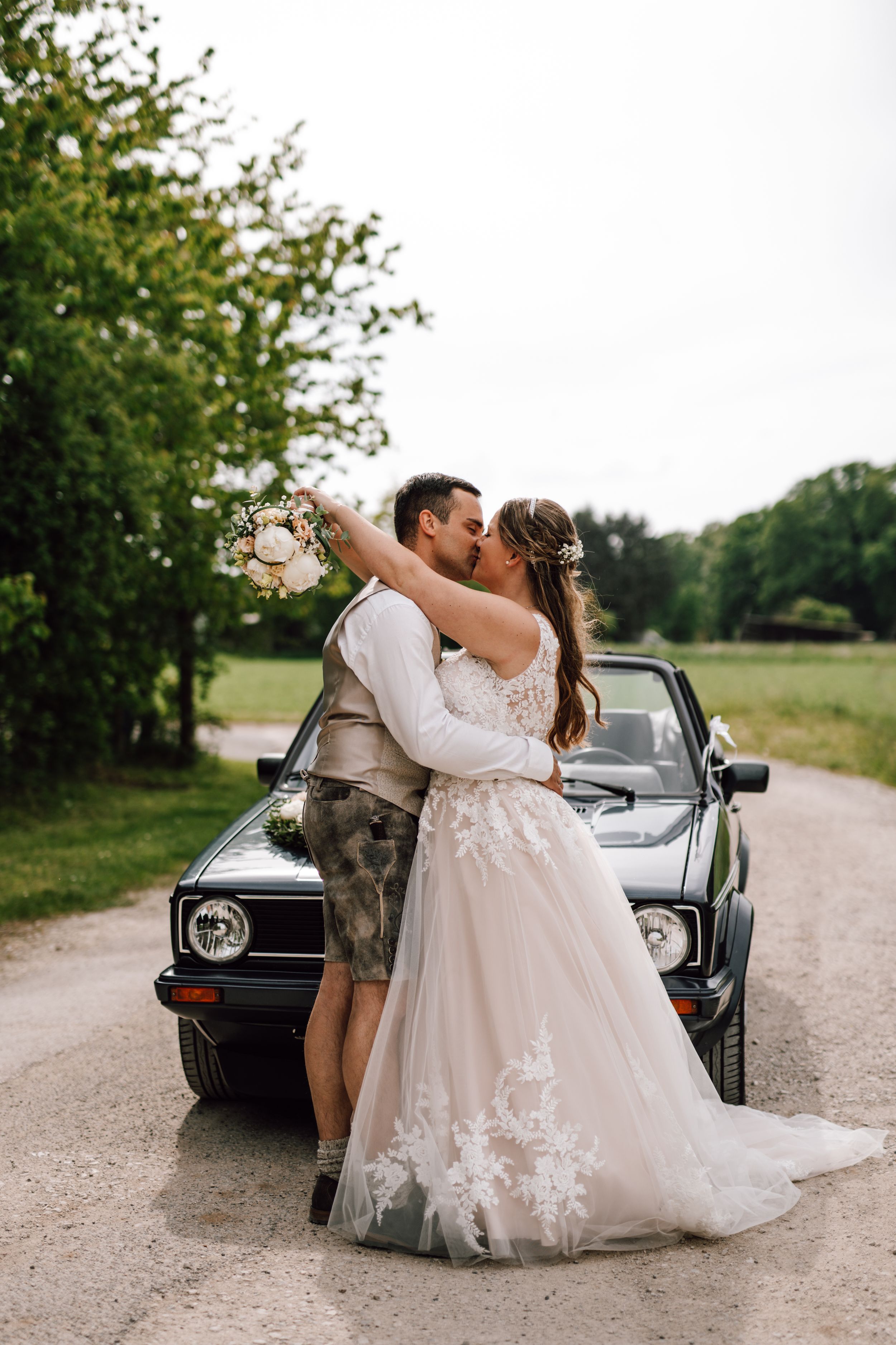 Elegant wedding portraits featuring a classic car and romantic poses on a country road.