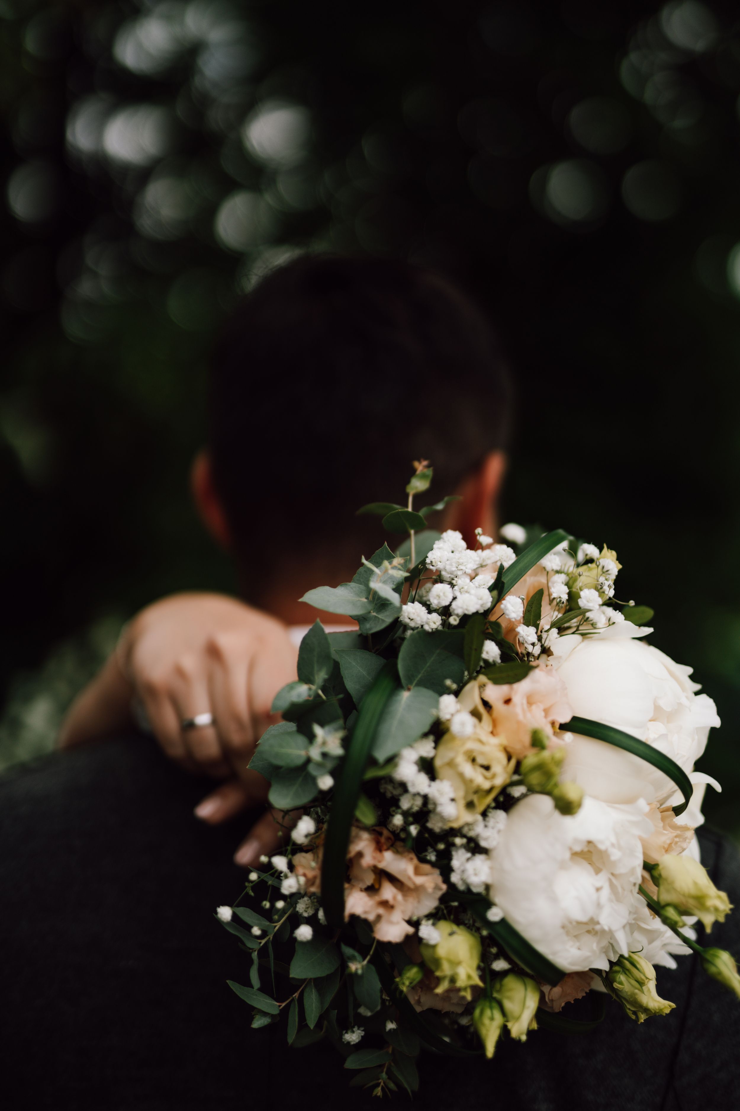 Close-up of a delicate white and green wedding bouquet with eucalyptus leaves.