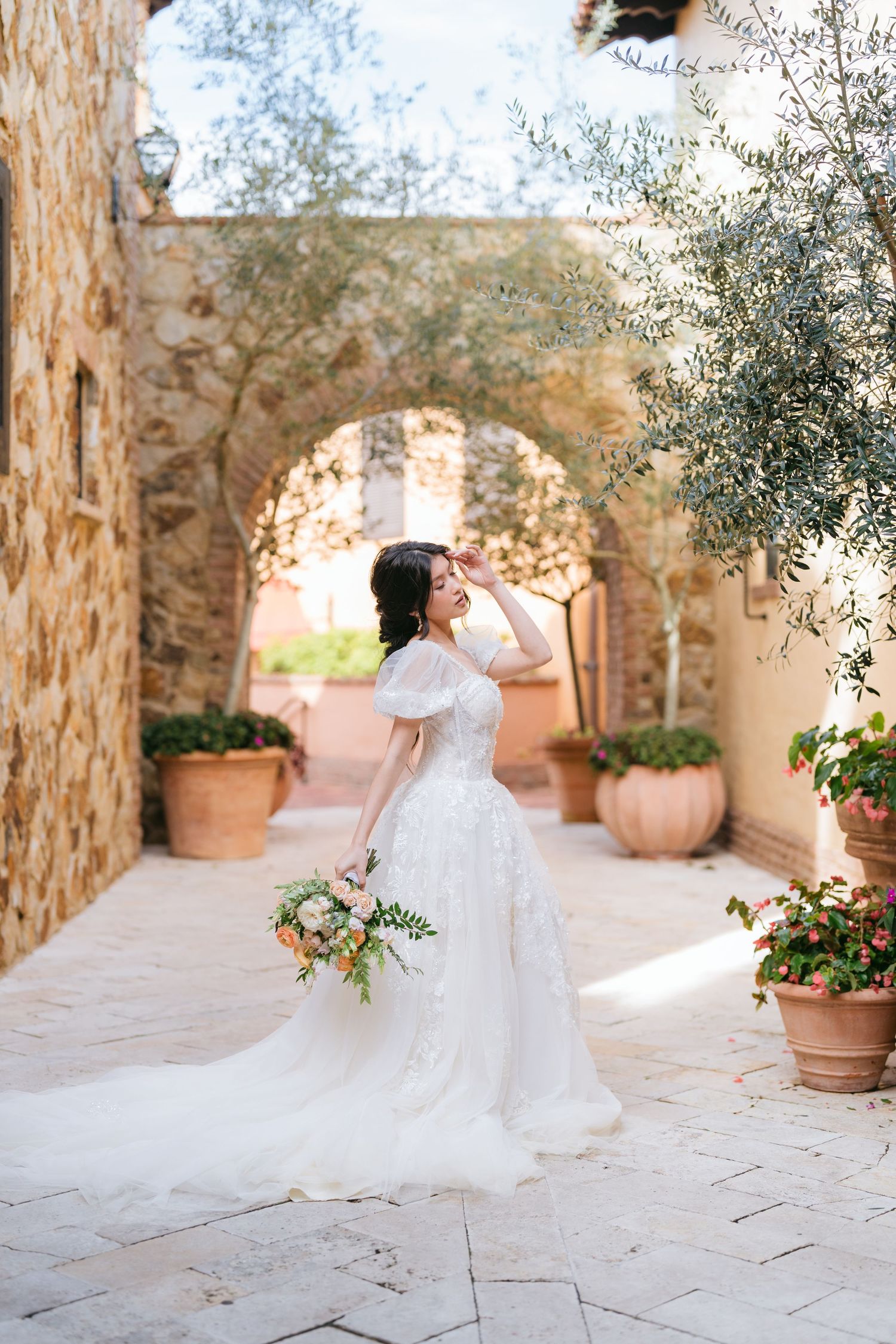Ethereal bridal portraits in a sunlit stone courtyard with flowing white dress.