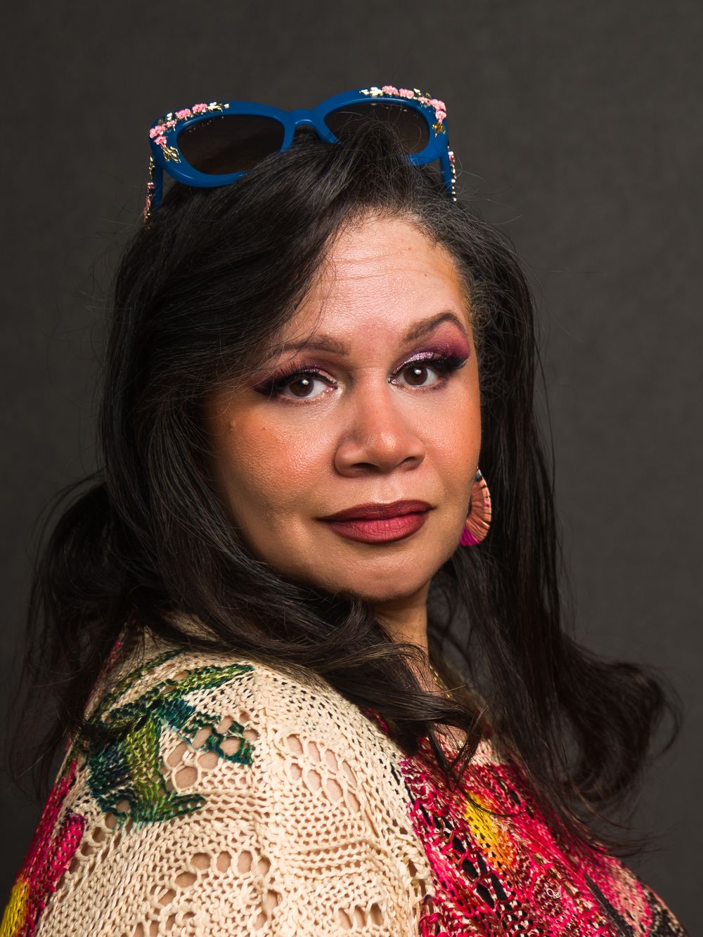 Artistic portrait series showing vibrant makeup and accessories against dark background with dramatic lighting.