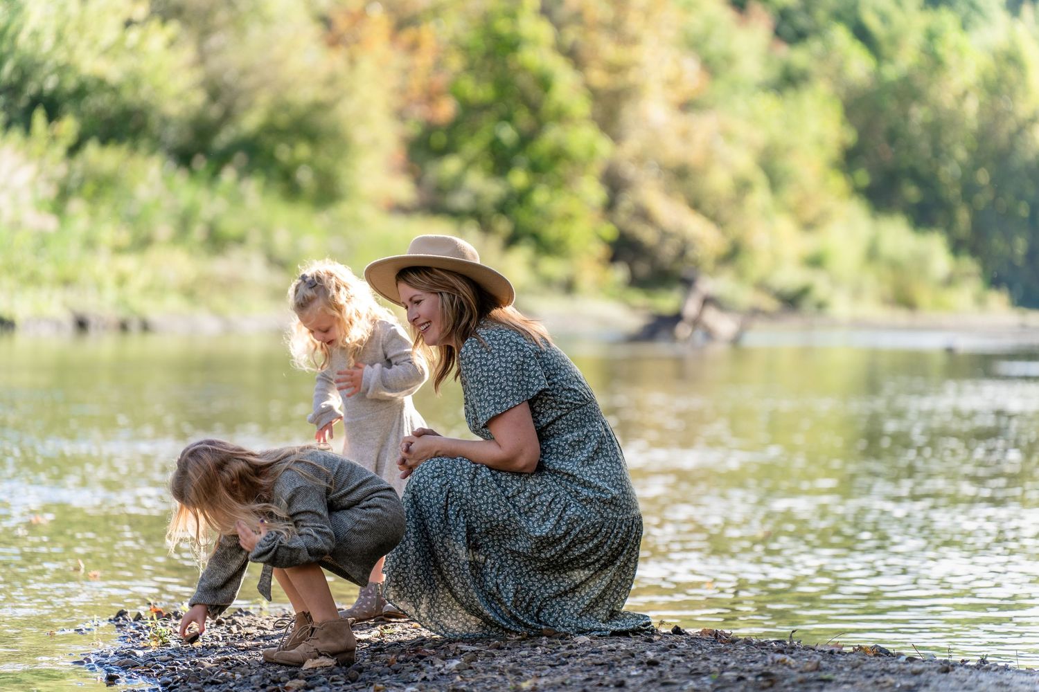 A parent and child share joyful laughter together while embracing in a sun-dappled forest setting. Stow, Ohio