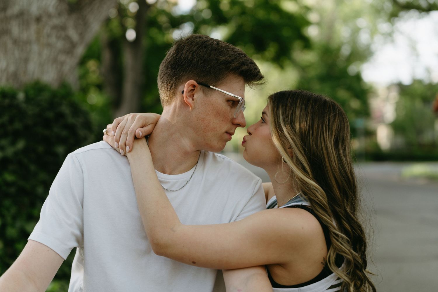 Intimate outdoor portrait of couple embracing on tree-lined path.