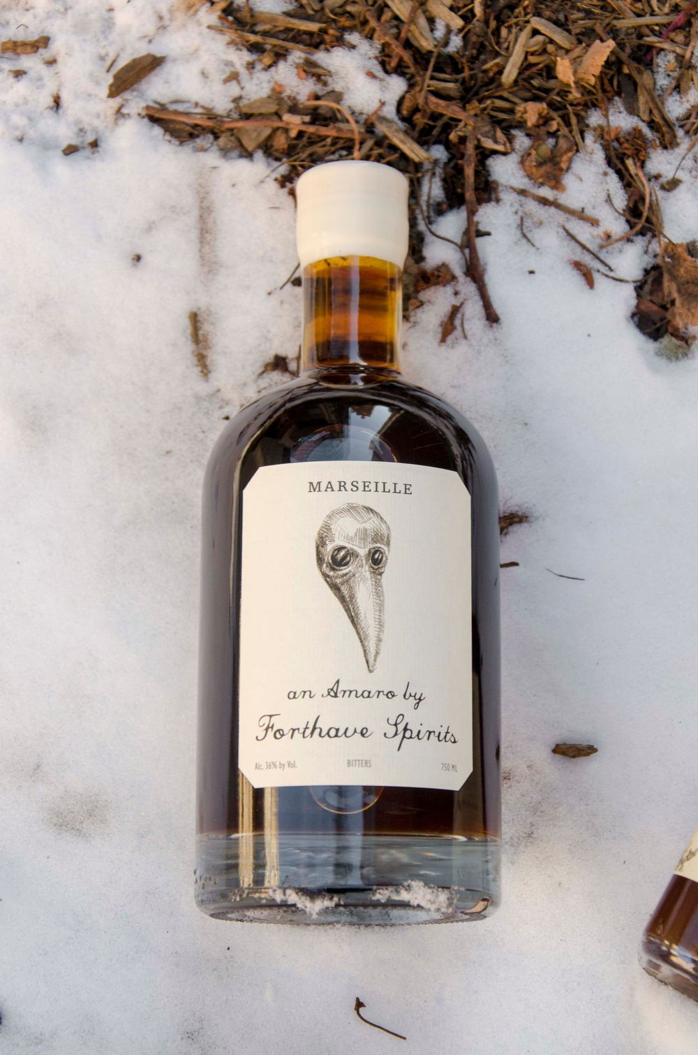 Bottle of Marseille amaro by Forthave Spirits photographed in snowy setting.