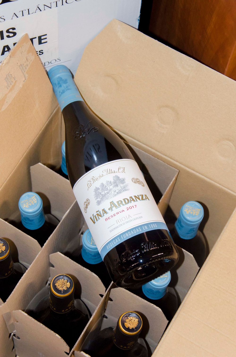 Wine bottles nestled in a cardboard box showing Vina Ardanza label and blue screw-cap bottles.