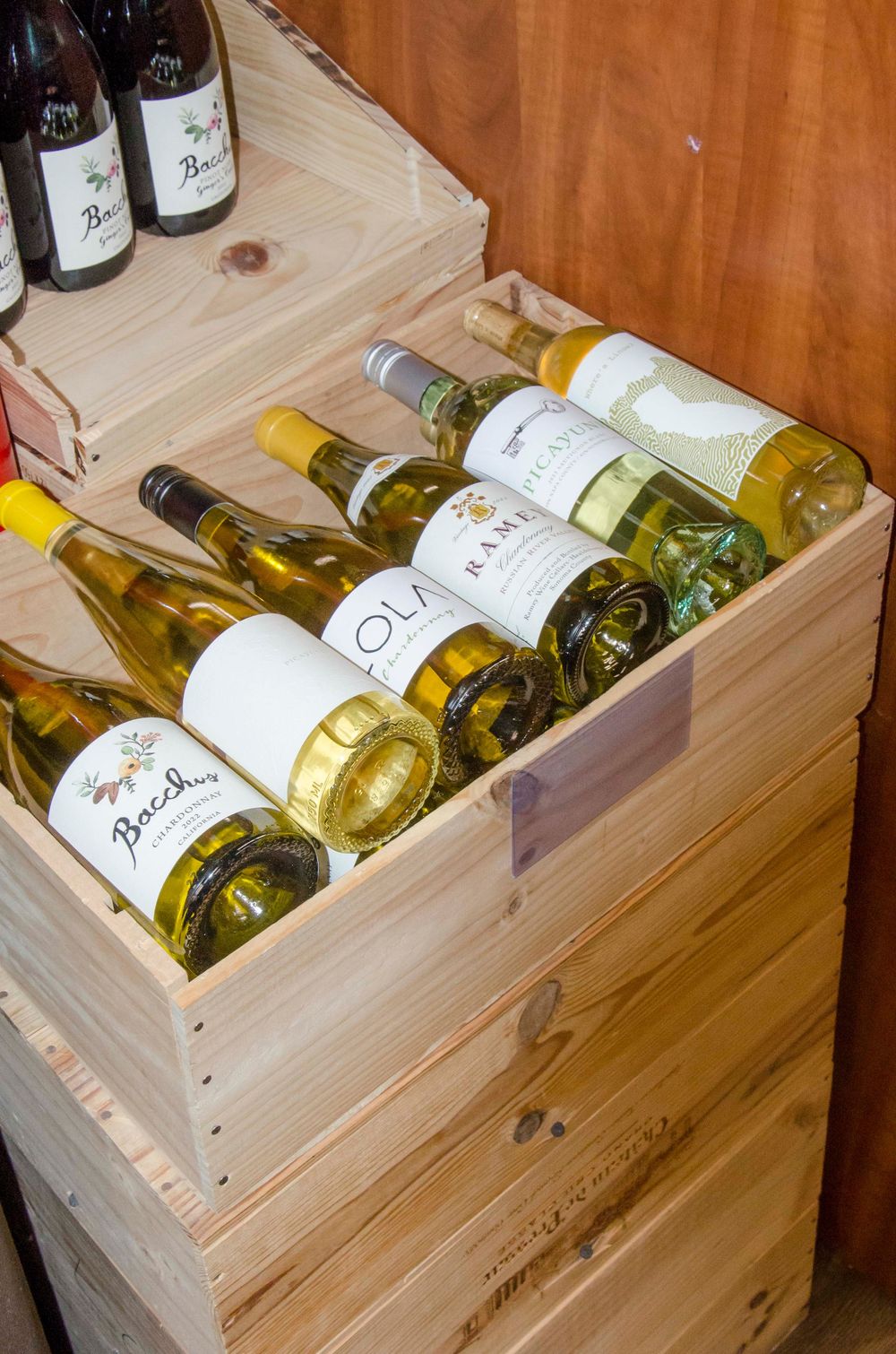 Wooden wine crates display neatly arranged white wine bottles laid horizontally in storage.