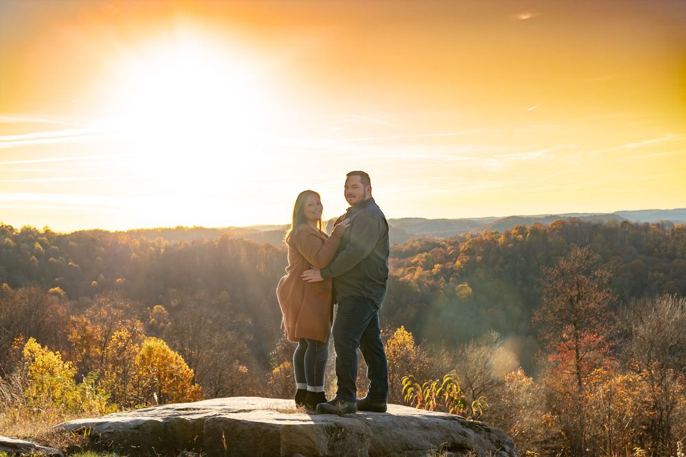 Panoramic sunset view with couple sitting on mountain overlook.